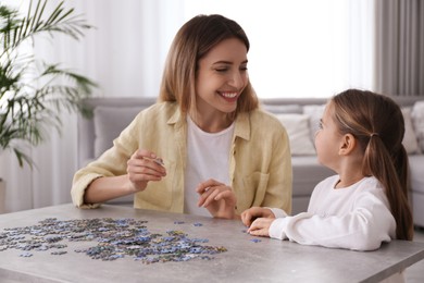 Photo of Woman and his little daughter playing with puzzles at home