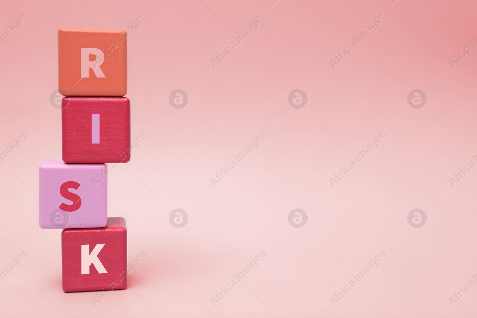 Photo of Stack of color wooden cubes with word Risk on light grey background. Space for text