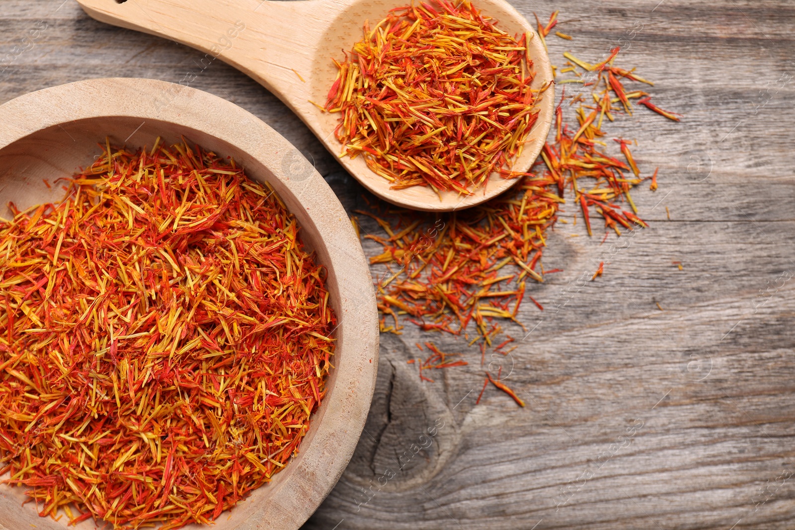 Photo of Aromatic saffron in bowl and spoon on wooden table, flat lay. Space for text