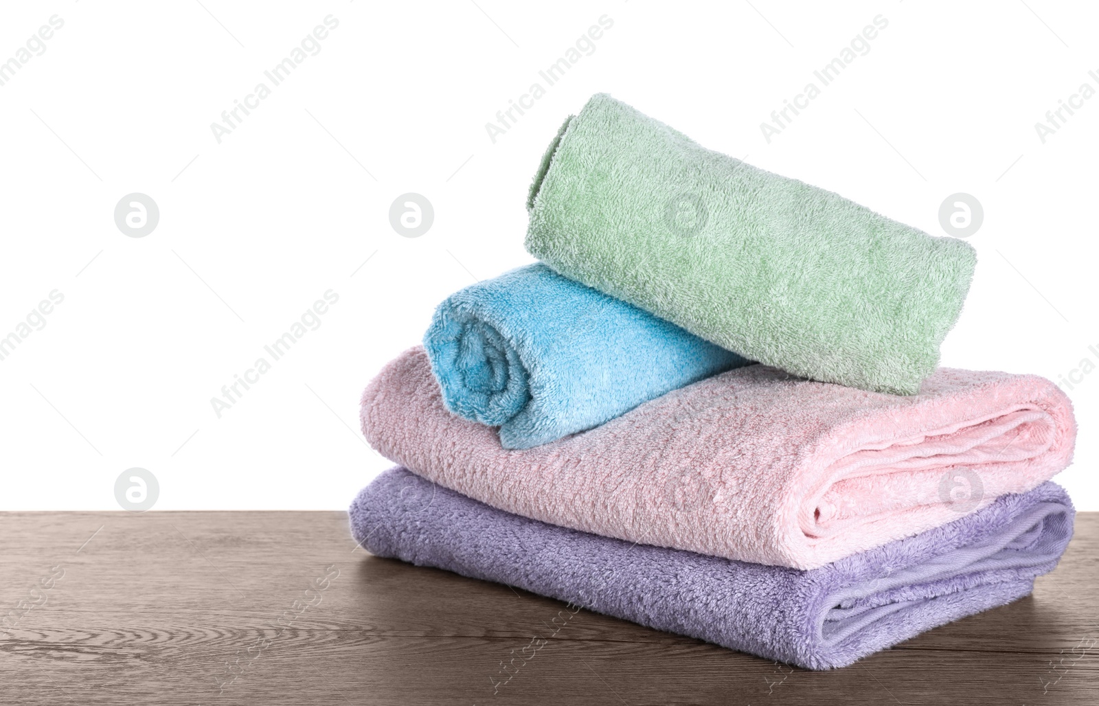 Photo of Fresh towels on wooden table against white background