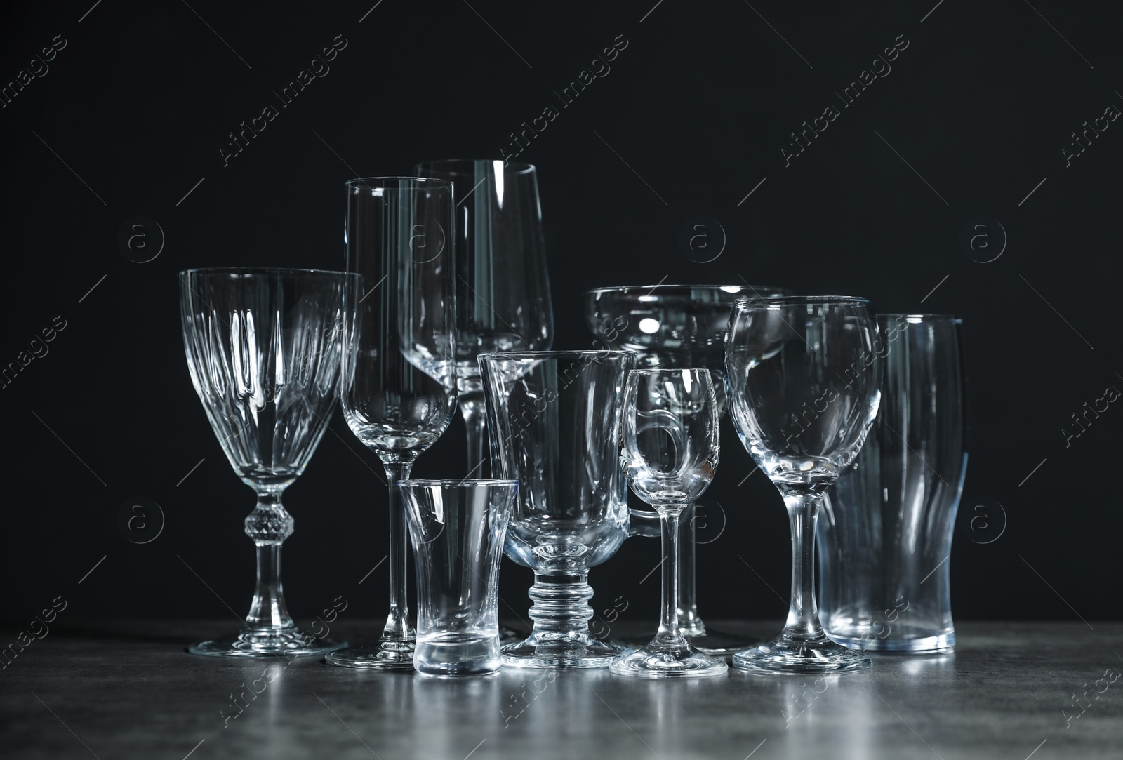 Photo of Set of bar glassware on table against dark background