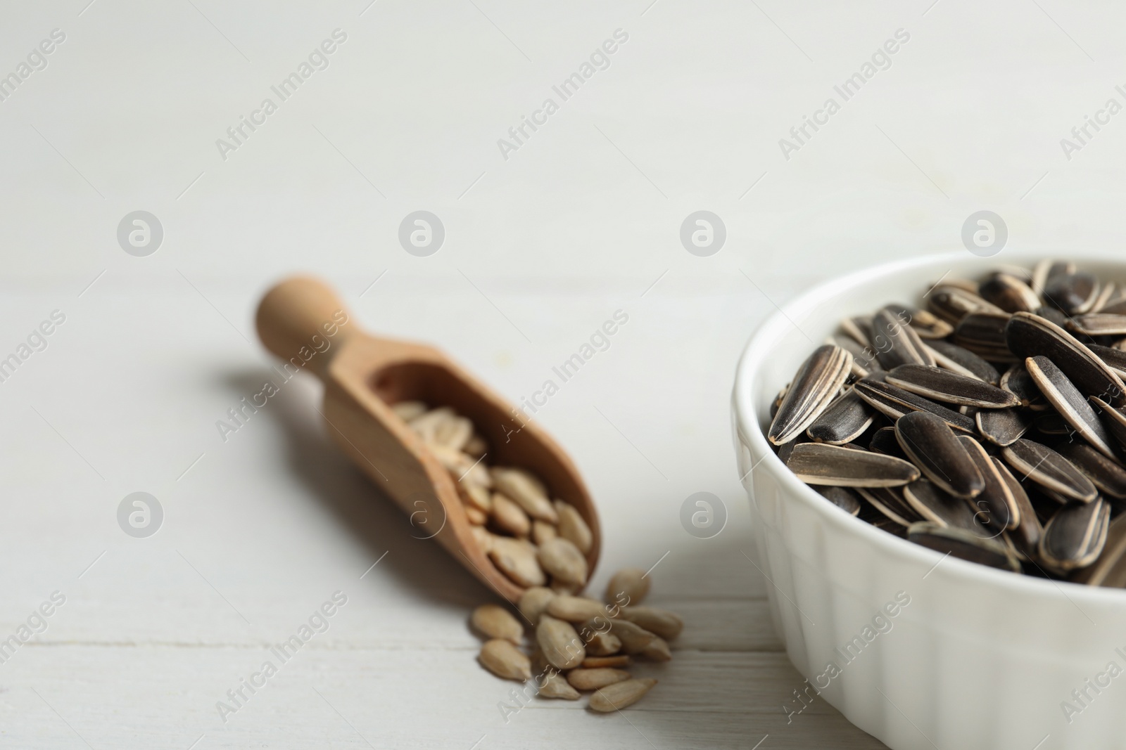 Photo of Organic sunflower seeds on white wooden table, closeup