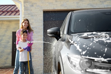 Photo of Mother and son washing car at backyard on sunny day