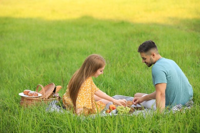 Happy young couple having picnic on green grass in park