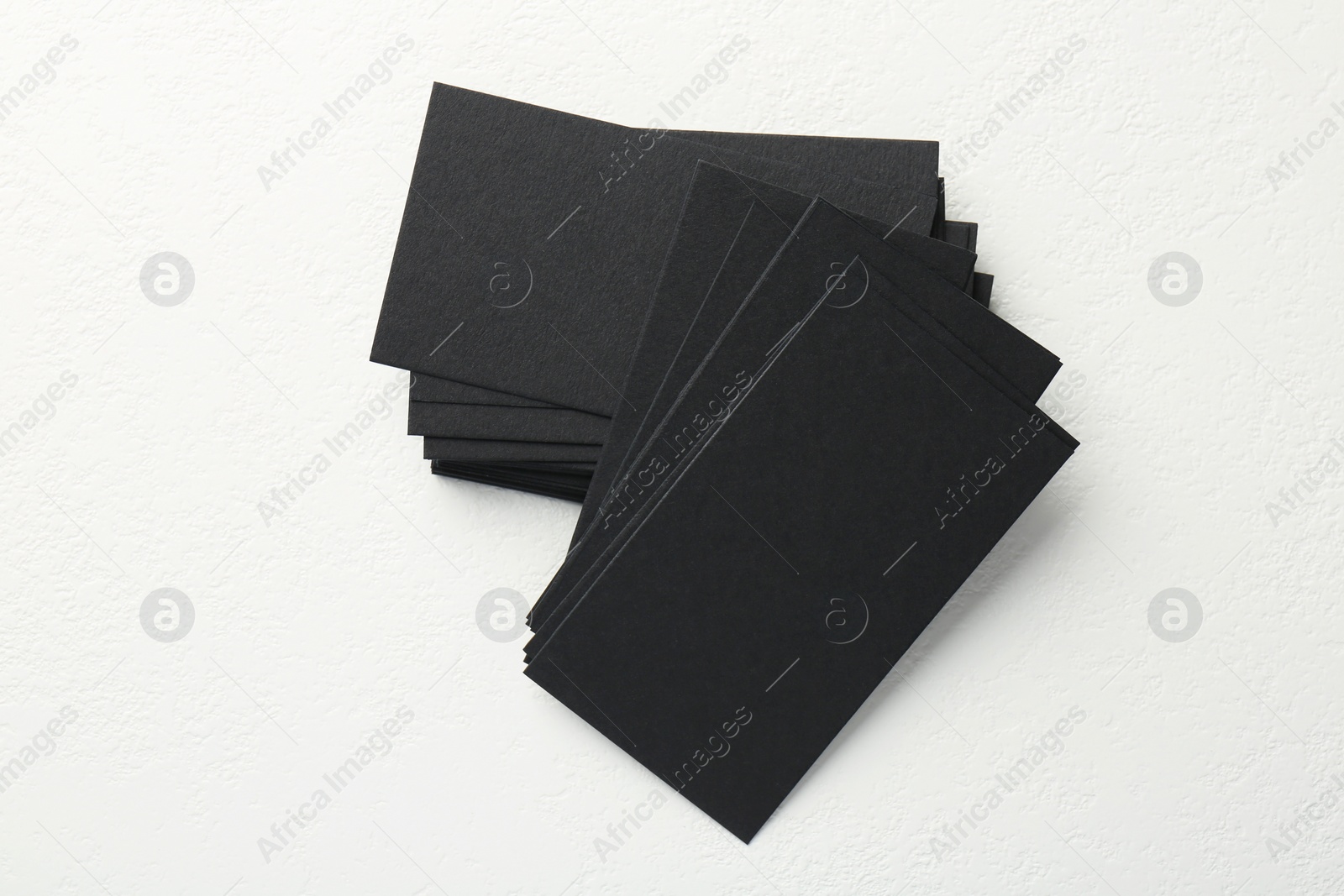 Photo of Blank black business cards on white table, top view