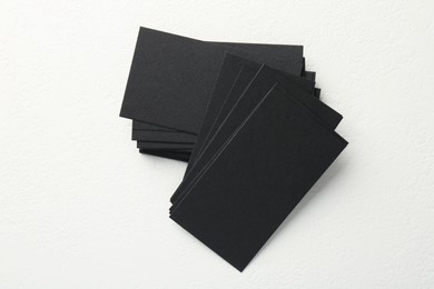 Blank black business cards on white table, top view