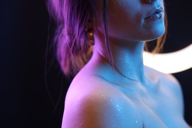 Woman on dark background in neon lights, closeup. Space for text