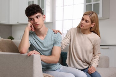 Mother consoling her upset son at home. Teenager problems