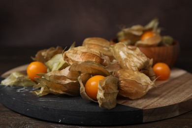 Photo of Ripe physalis fruits with calyxes on wooden table, closeup