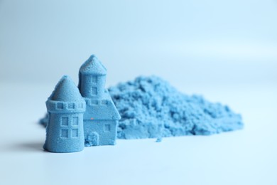 Photo of Castle figures made of kinetic sand on light blue background, closeup. Space for text