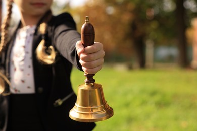 Photo of Pupil holding school bell outdoors on sunny day, closeup. Space for text