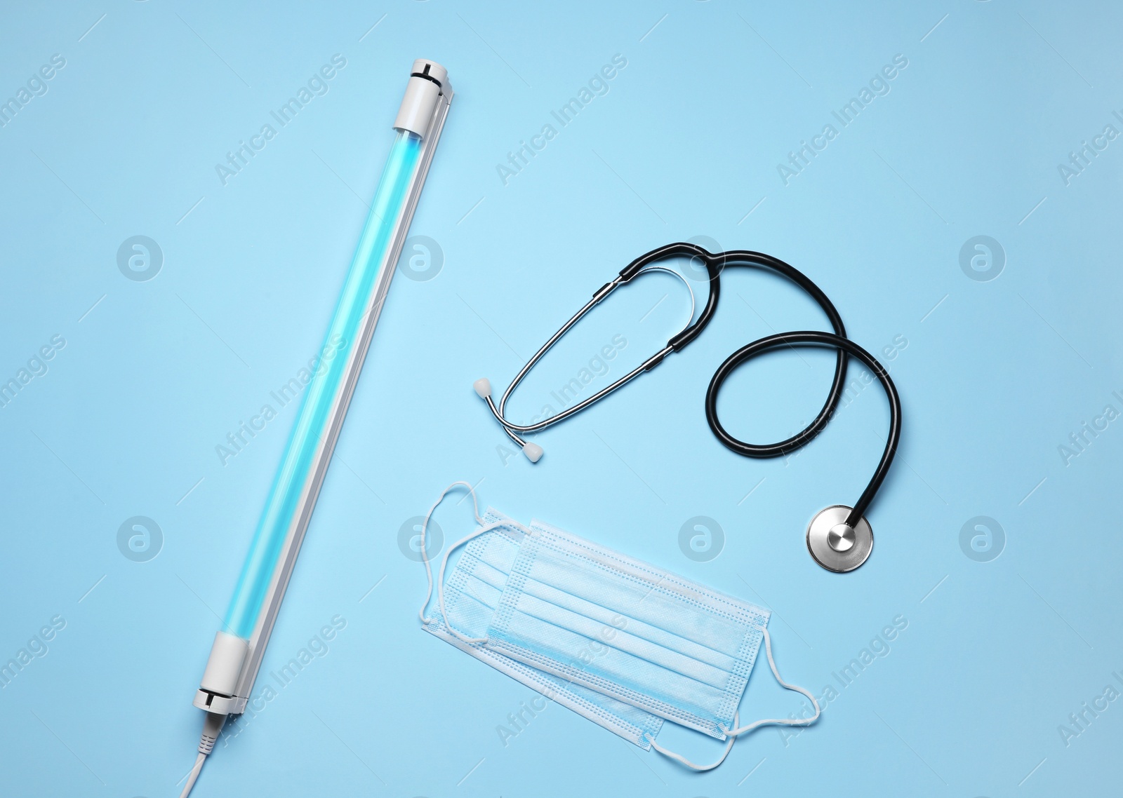 Photo of Flat lay composition with ultraviolet lamp on light blue background