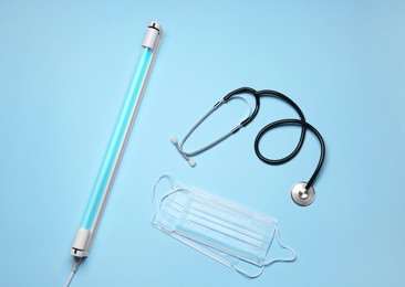 Flat lay composition with ultraviolet lamp on light blue background