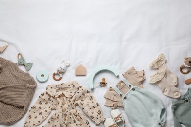 Photo of Layout with baby outfit and cute accessories on white bed, top view. space for text