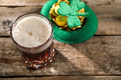 Photo of St. Patrick's day celebration. Green beer, leprechaun hat with gold and decorative clover leaf on wooden table. Space for text