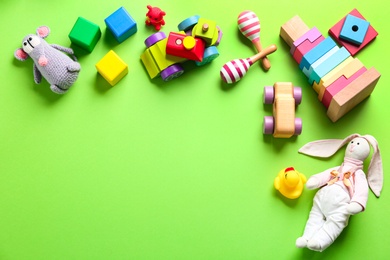 Photo of Different toys on green background, flat lay. Space for text