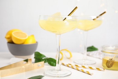 Photo of Delicious bee's knees cocktails and ingredients on white table