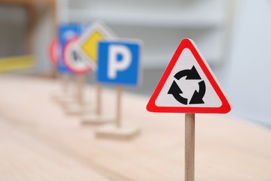 Photo of Different miniature road signs on wooden table, closeup with space for text. Montessori toy