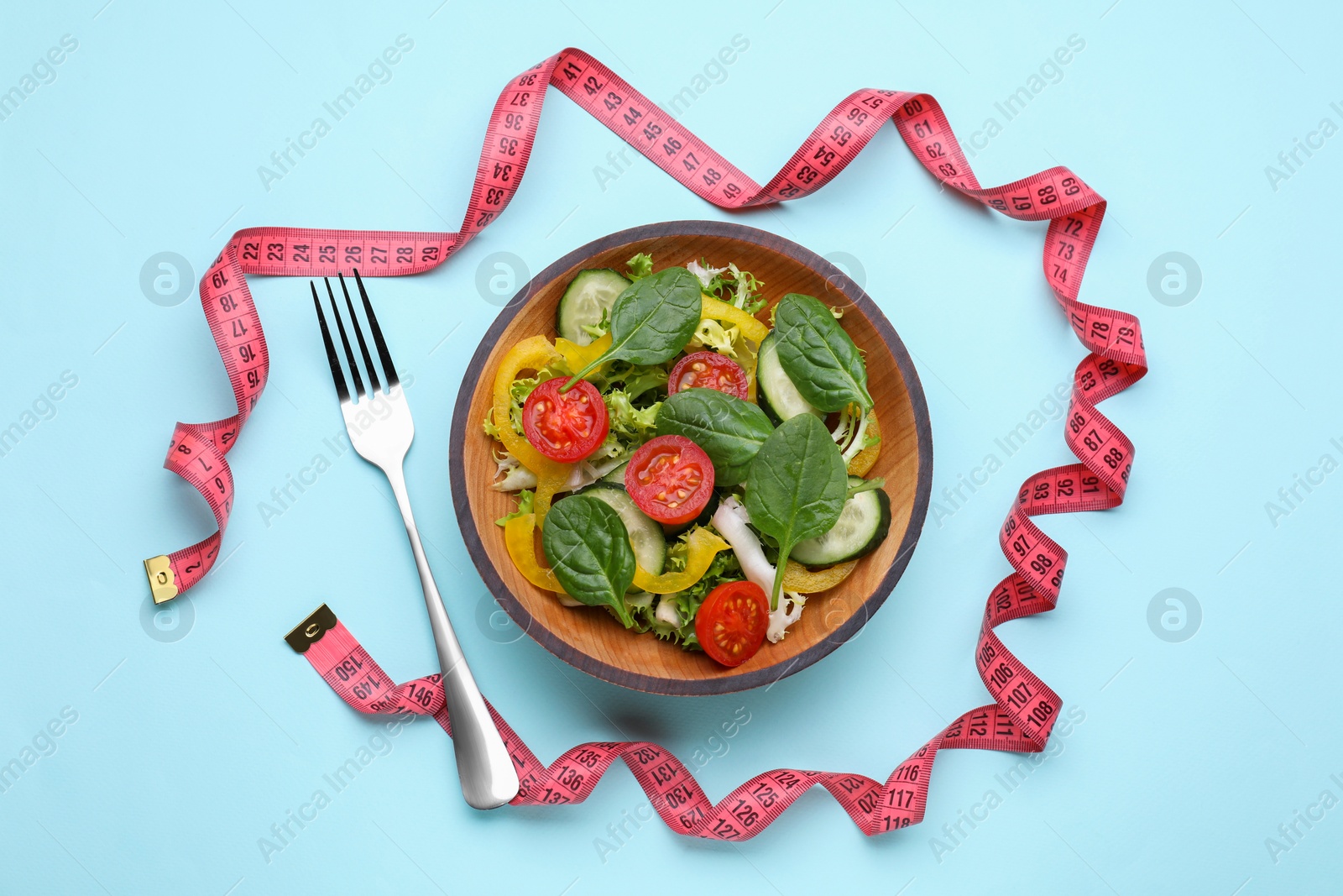 Photo of Measuring tape, salad and fork on light blue background, flat lay