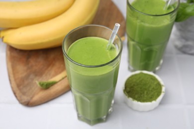 Photo of Glasses of tasty matcha smoothie on white table, closeup