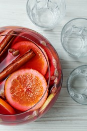 Photo of Empty glasses near bowl of aromatic punch drink on white wooden table, flat lay