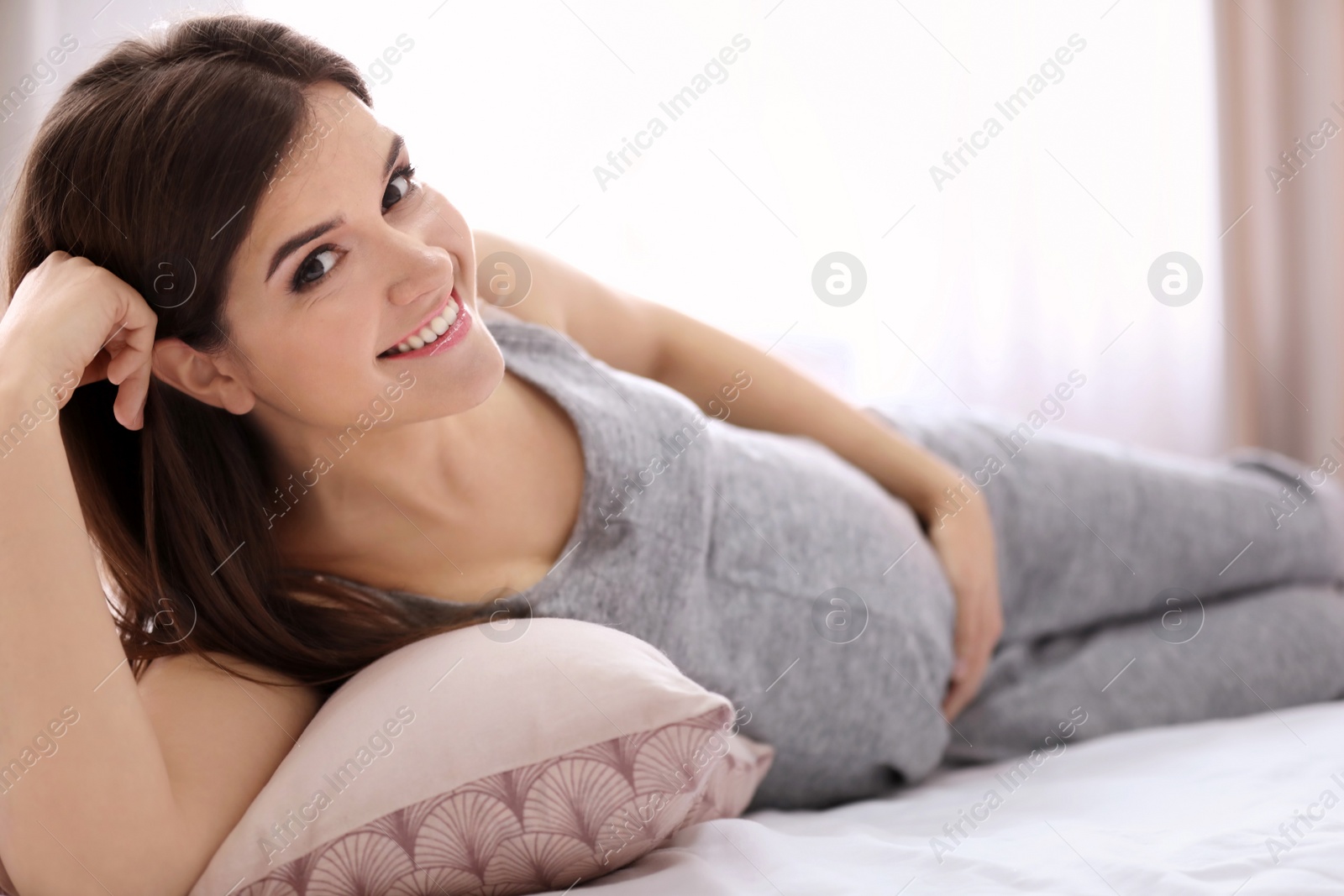 Photo of Young pregnant woman lying on bed at home