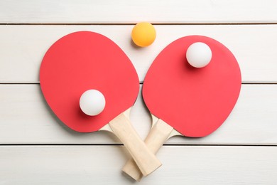 Photo of Ping pong rackets and balls on white wooden table, flat lay