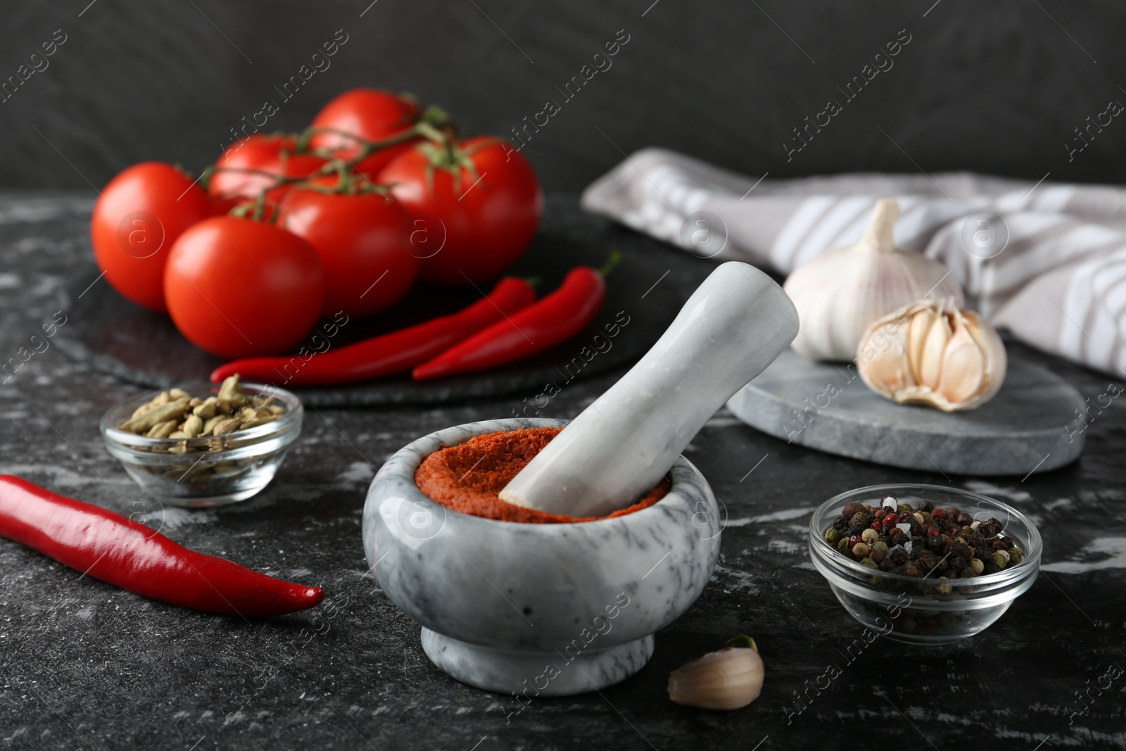 Photo of Mortar with red curry paste and ingredients on black textured table