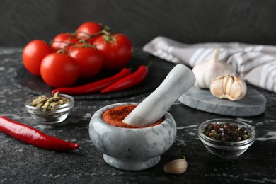 Photo of Mortar with red curry paste and ingredients on black textured table