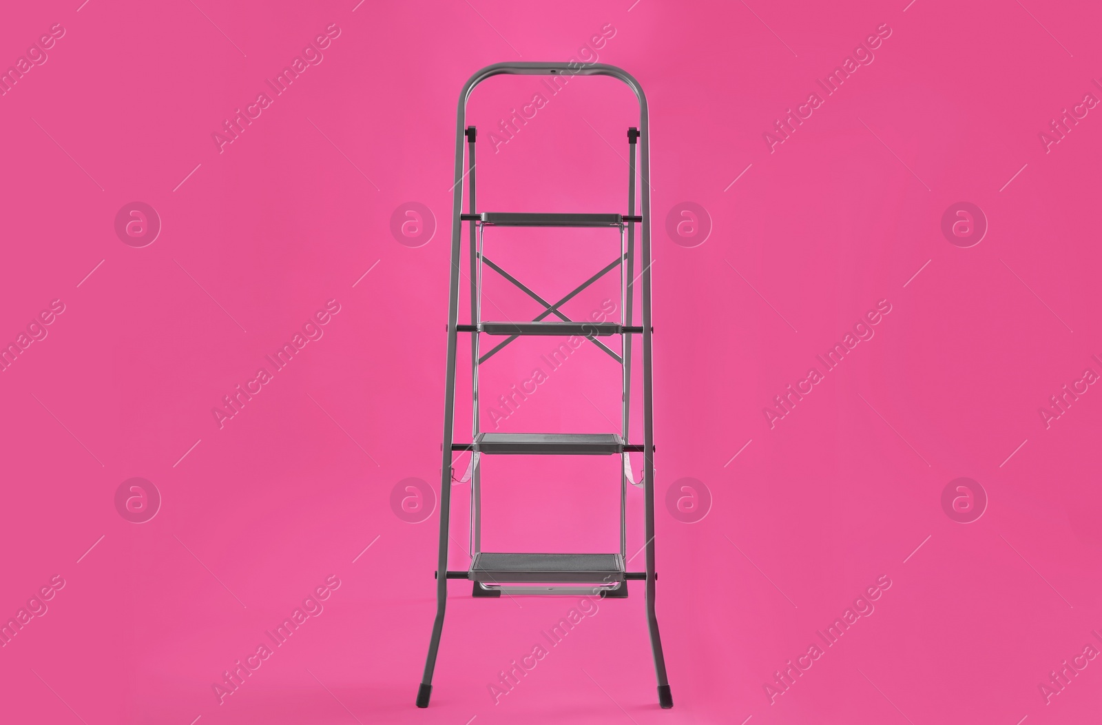 Photo of Modern metal stepladder on pink background. Construction tool