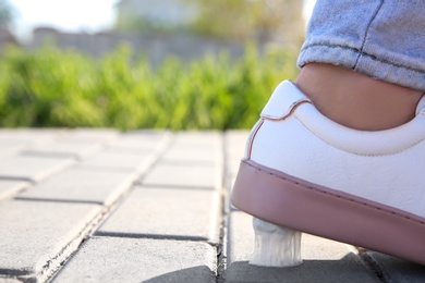 Photo of Woman stepping in chewing gum on sidewalk. Concept of stickiness