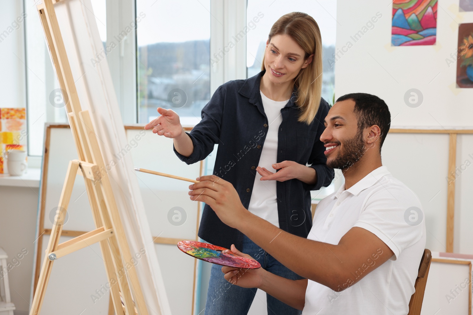 Photo of Artist teaching her student to paint in studio. Creative hobby