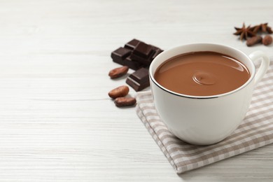 Yummy hot chocolate in cup on white wooden table. Space for text