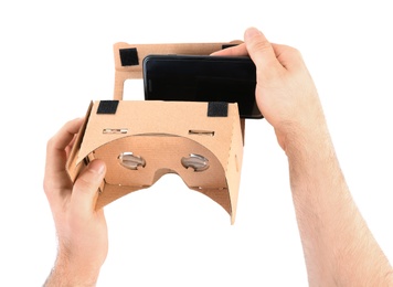 Photo of Man putting smartphone into cardboard virtual reality headset on white background, closeup