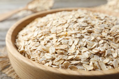 Photo of Wooden bowl with oatmeal on table, closeup