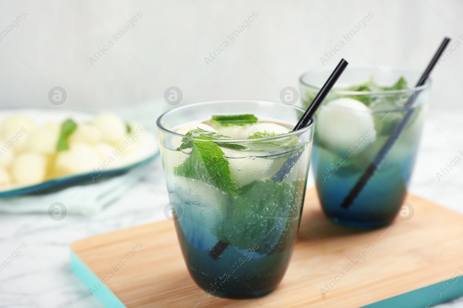 Photo of Glasses with tasty melon ball drinks on table