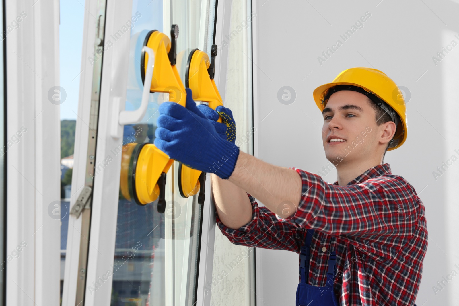Photo of Worker using suction lifters during plastic window installation indoors