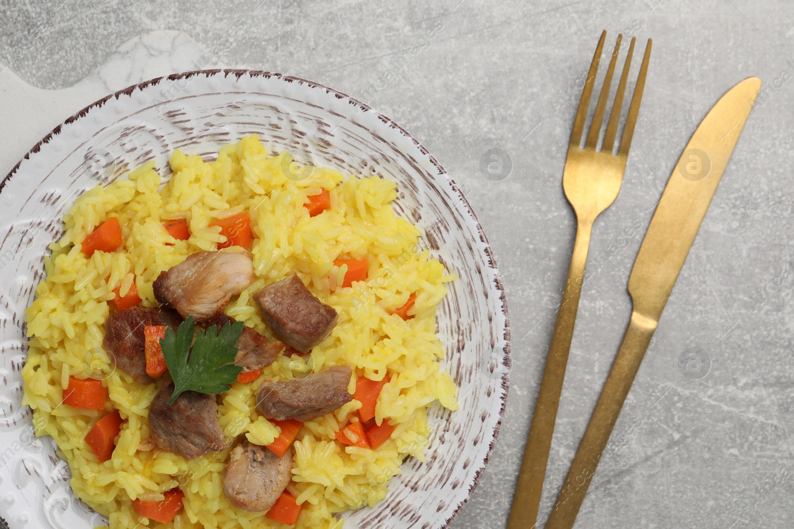 Photo of Delicious pilaf with meat served on light grey table, flat lay