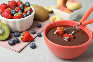 Photo of Fondue pot with chocolate and different products on grey table