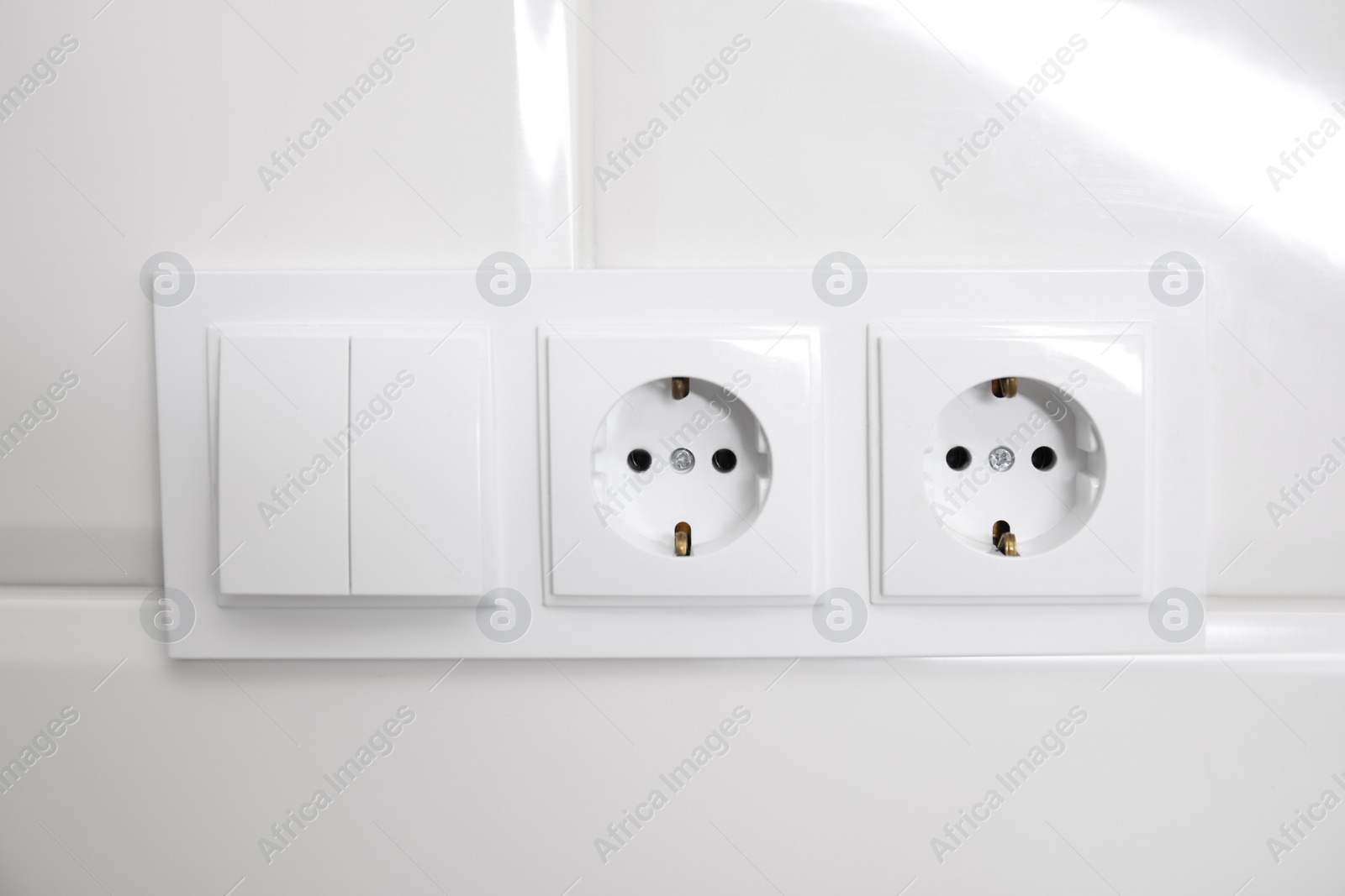 Photo of Light switch and power sockets on white wall indoors