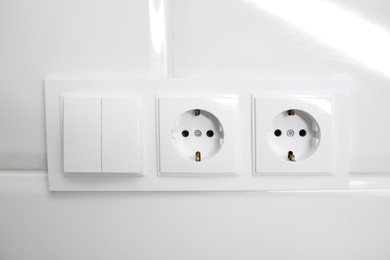 Photo of Light switch and power sockets on white wall indoors