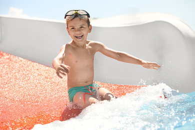 Photo of Little boy on slide at water park. Summer vacation