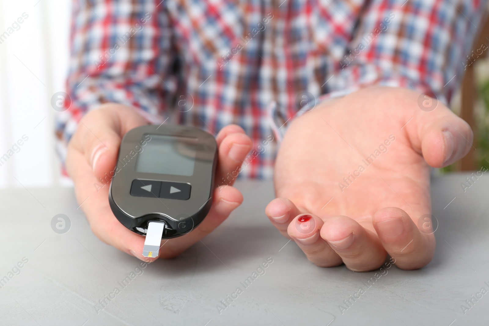 Photo of Man checking blood sugar level with glucometer at table. Diabetes test