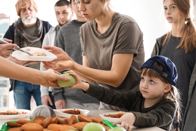 Poor people receiving food from volunteers indoors