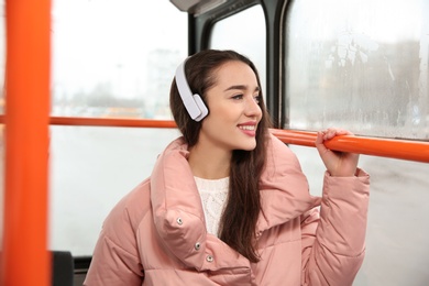 Beautiful young woman listening to music with headphones in public transport