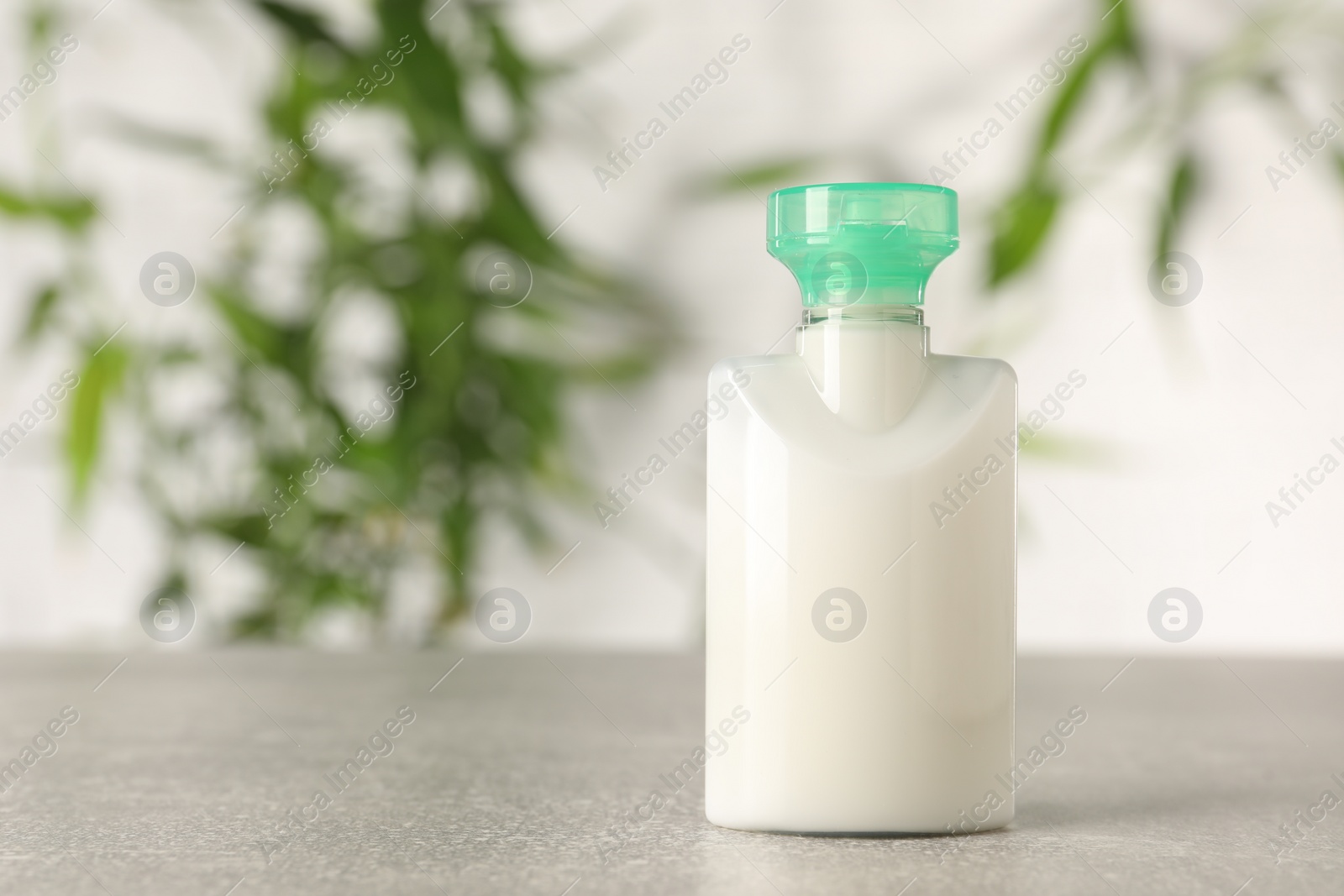 Photo of Mini bottle of cosmetic product on light grey table against blurred background, closeup. Space for text