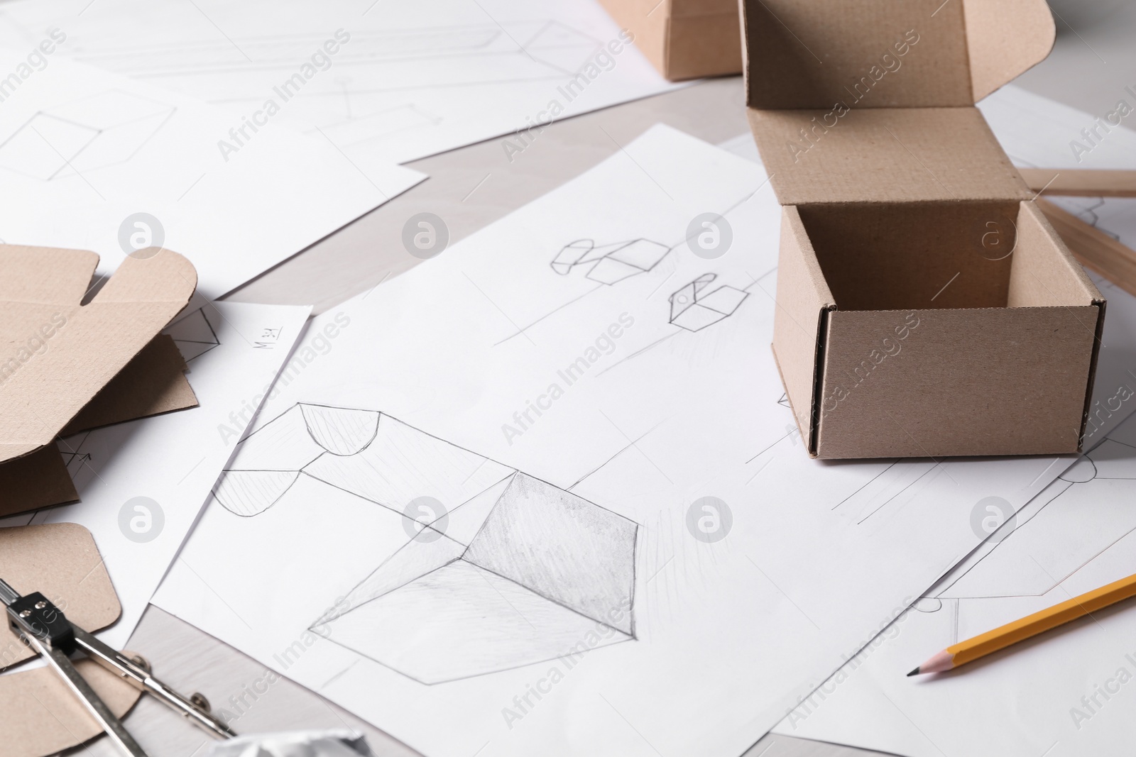 Photo of Creating packaging design. Drawings, boxes and stationery on table, closeup