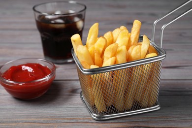 Tasty French fries, soda and ketchup on grey wooden table, closeup