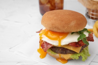 Photo of Delicious burger with fried egg on white table, closeup. Space for text