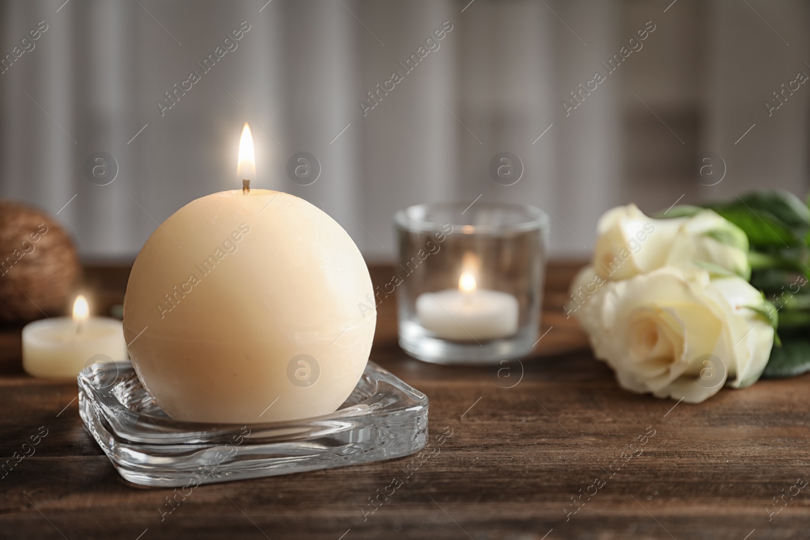 Photo of Glass stand with burning wax candle on wooden table